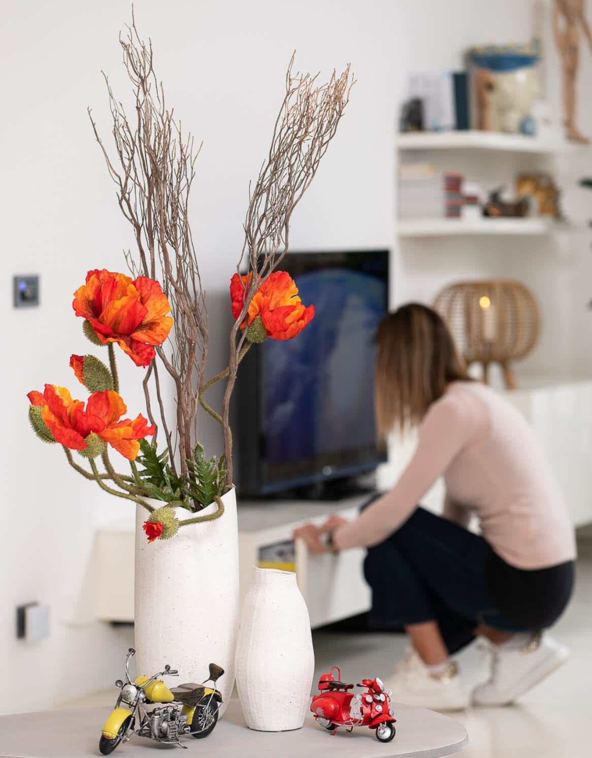 donna che apre un cassetto e in primo piano dei vasi con fiori